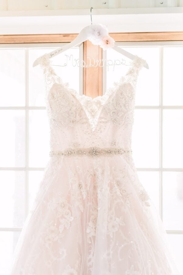 Wedding dress hanging on custom hanger.  Ivory lace dress with beading  and belt.