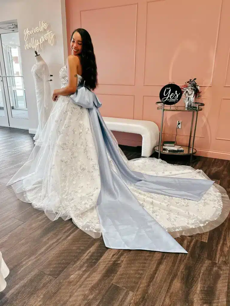 Bride Trying On Non Traditional Wedding Dress With Long Blue Bow