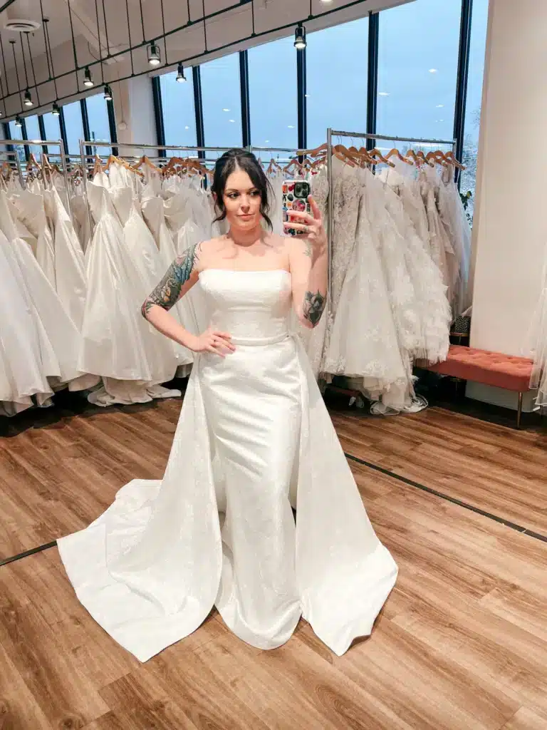 Women Posing In White Wedding Dress In Front Of Mirror With Detachable Bustle