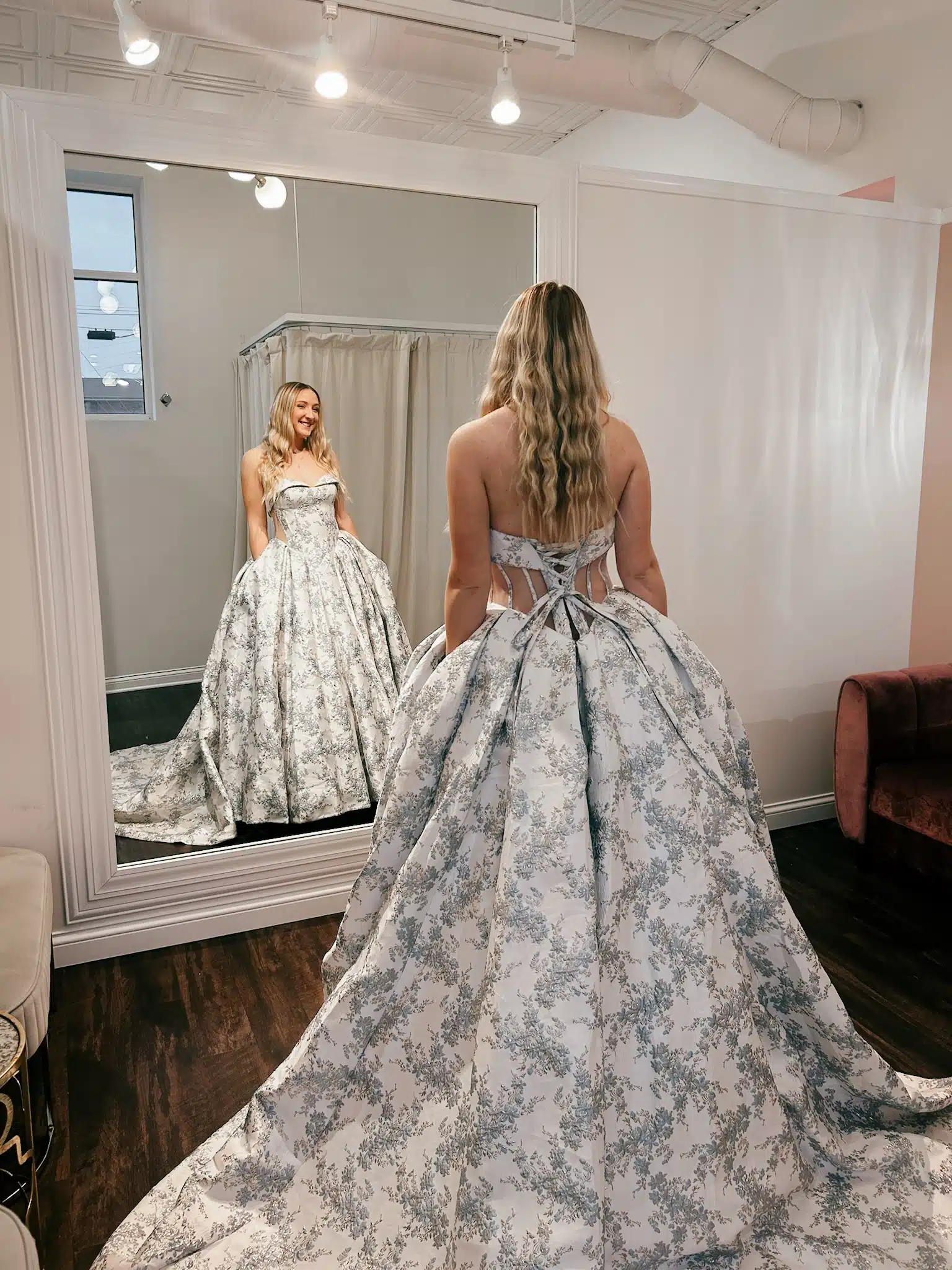 Bride Looking In Mirror Trying On Nontraditional Wedding Dress With Floral Pattern Bride Looking In Mirror Trying On Nontraditional Wedding Dress With Floral Pattern