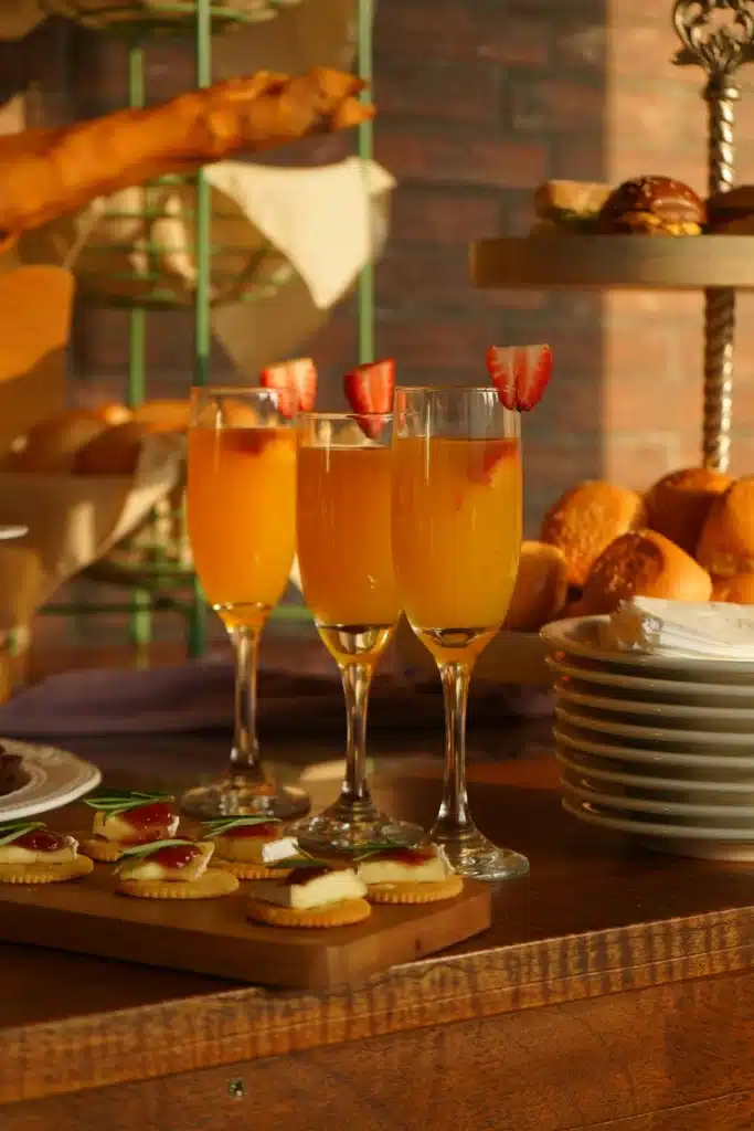 Sunset Themed Mimosa Bar With Pastries And Drinks On Table