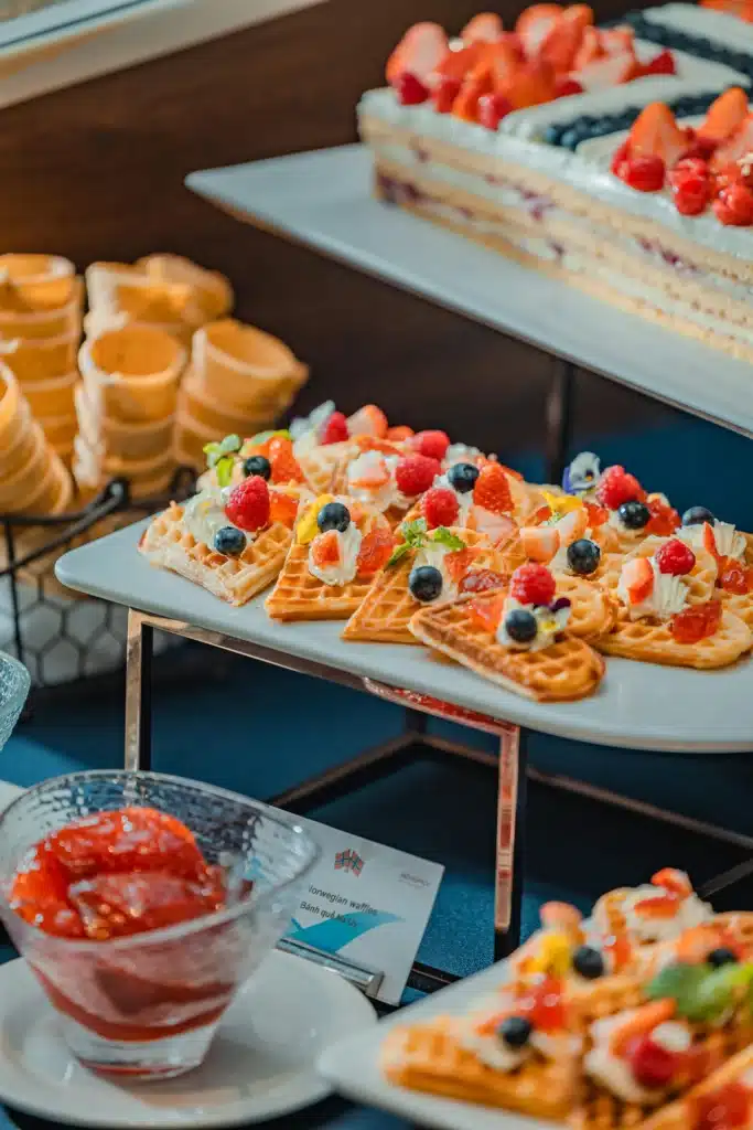Heart Shaped Waffles On Stand With Variety Of Desserts On Table For Waffle Bar Station