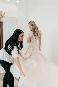 Women With Soft Beige Wedding Dress Getting Helped By Stylist