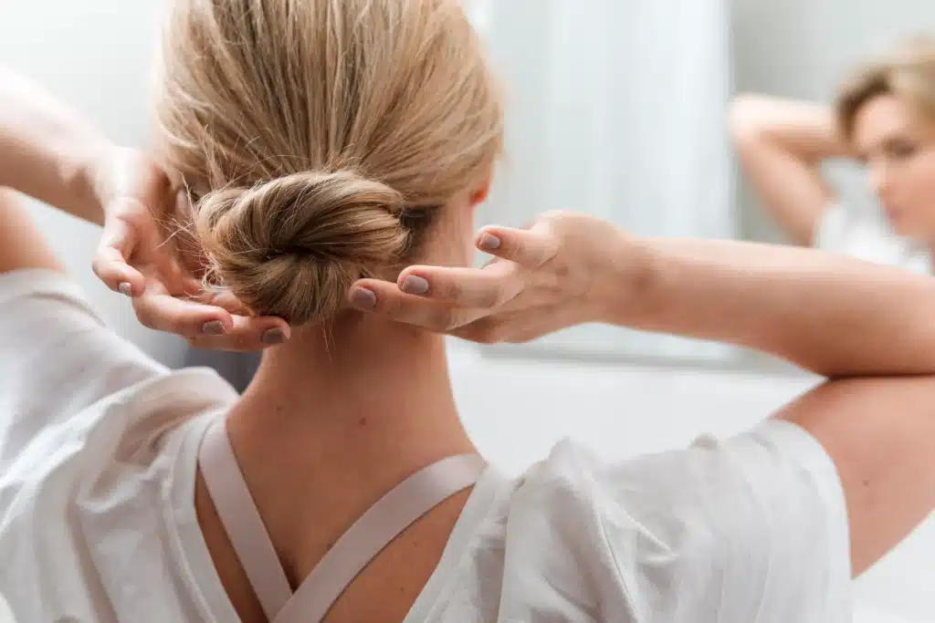 Women Fixing Sleek Bun Hairdo For Wedding Ceremony