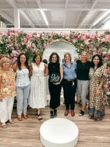Bride With Family Posing In Front Of Floral Backdrop After Saying Yes To A Wedding Dress From Sophias Bridal And Tux In Indianapolis