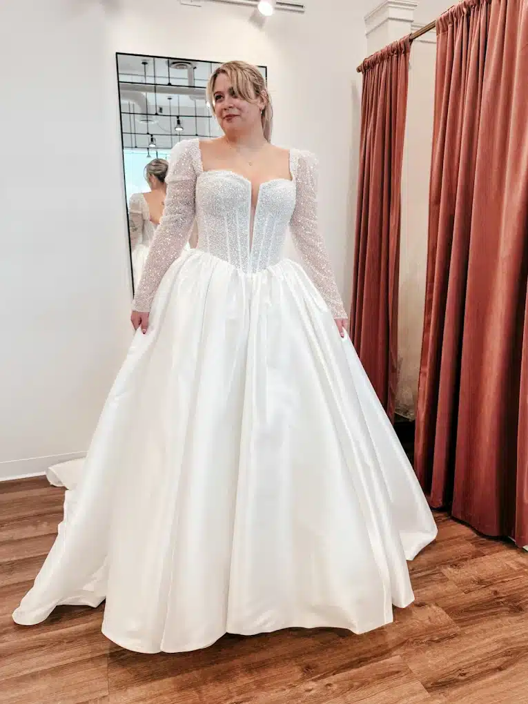 Client Trying On Wedding Dress With Long Sleeves And Sequins At Sophias Bridal Boutique