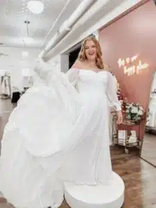 Women Trying On Affordable Wedding Dress In Store And Lifting Gown To Share Flare
