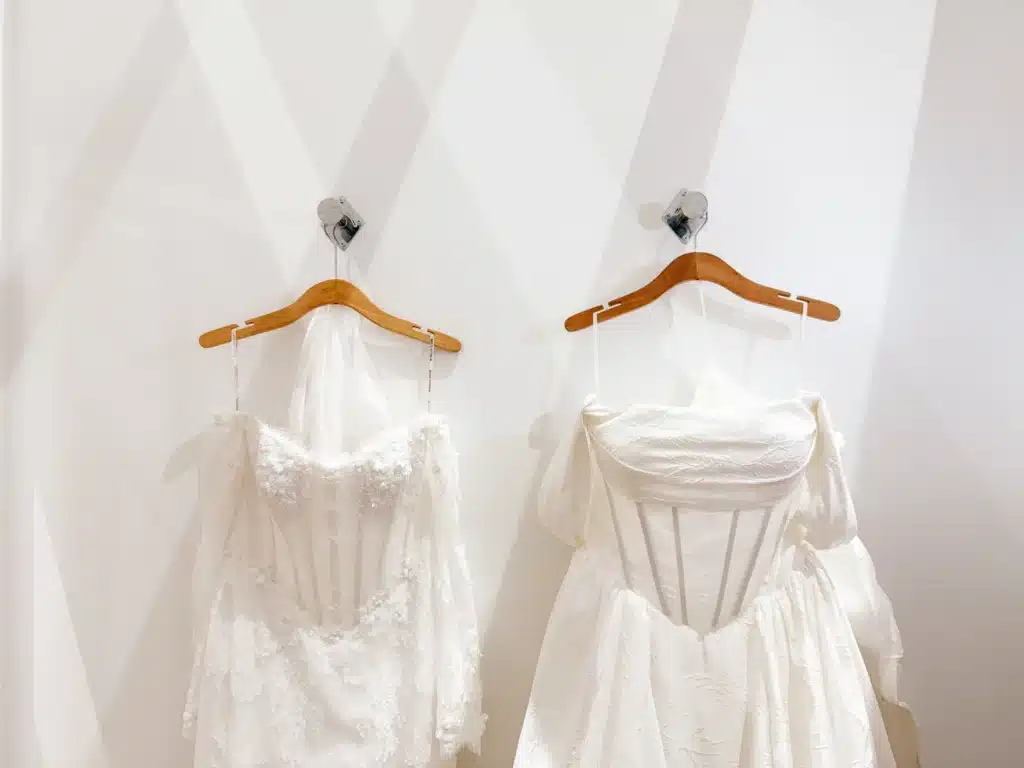 Two White Wedding Dresses On Hangers Hung Up In Dressing Room