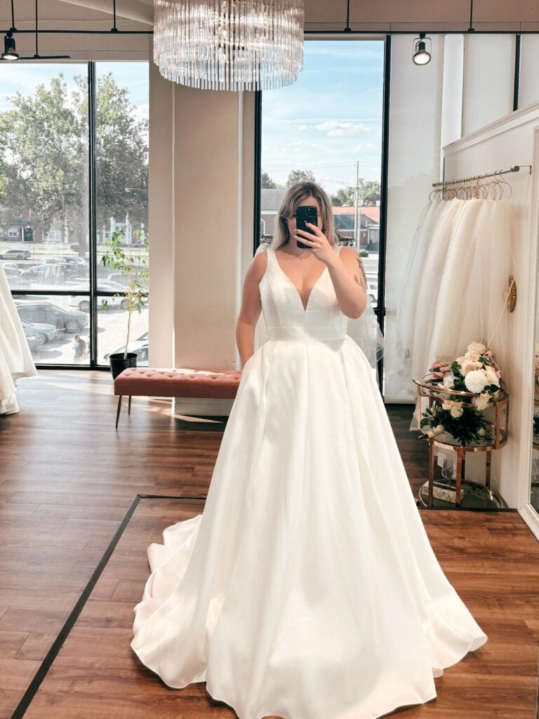 Bride taking a mirror selfie during her wedding dress fitting
