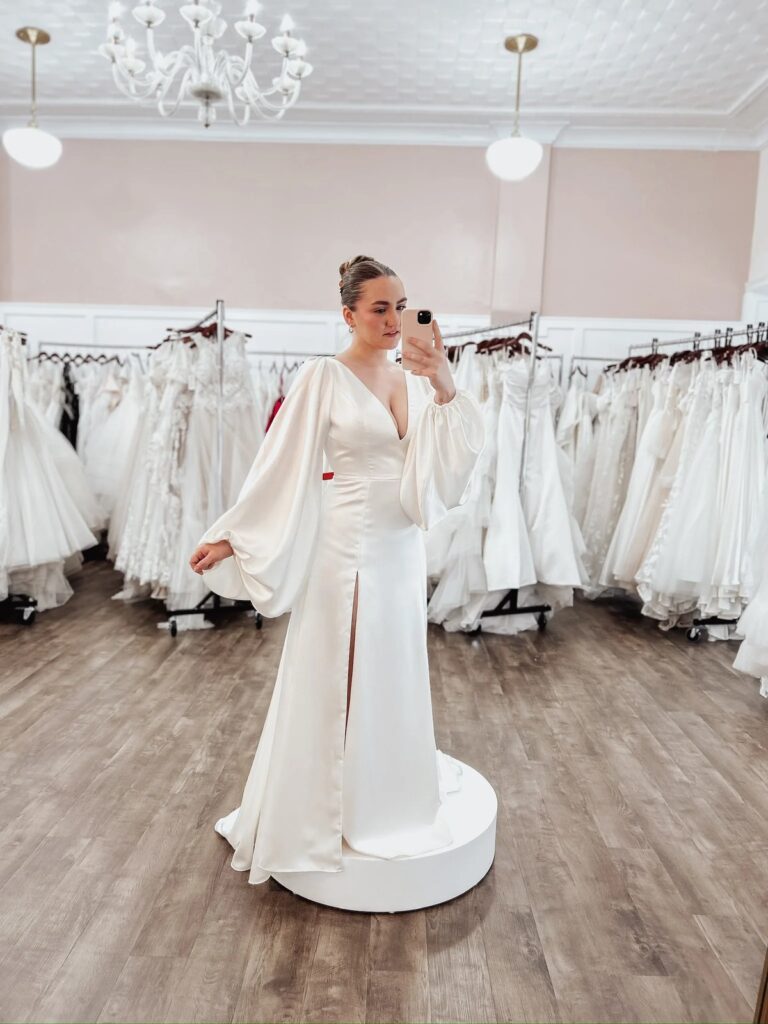 Bride posing in the mirror while trying on simple elopement dresses